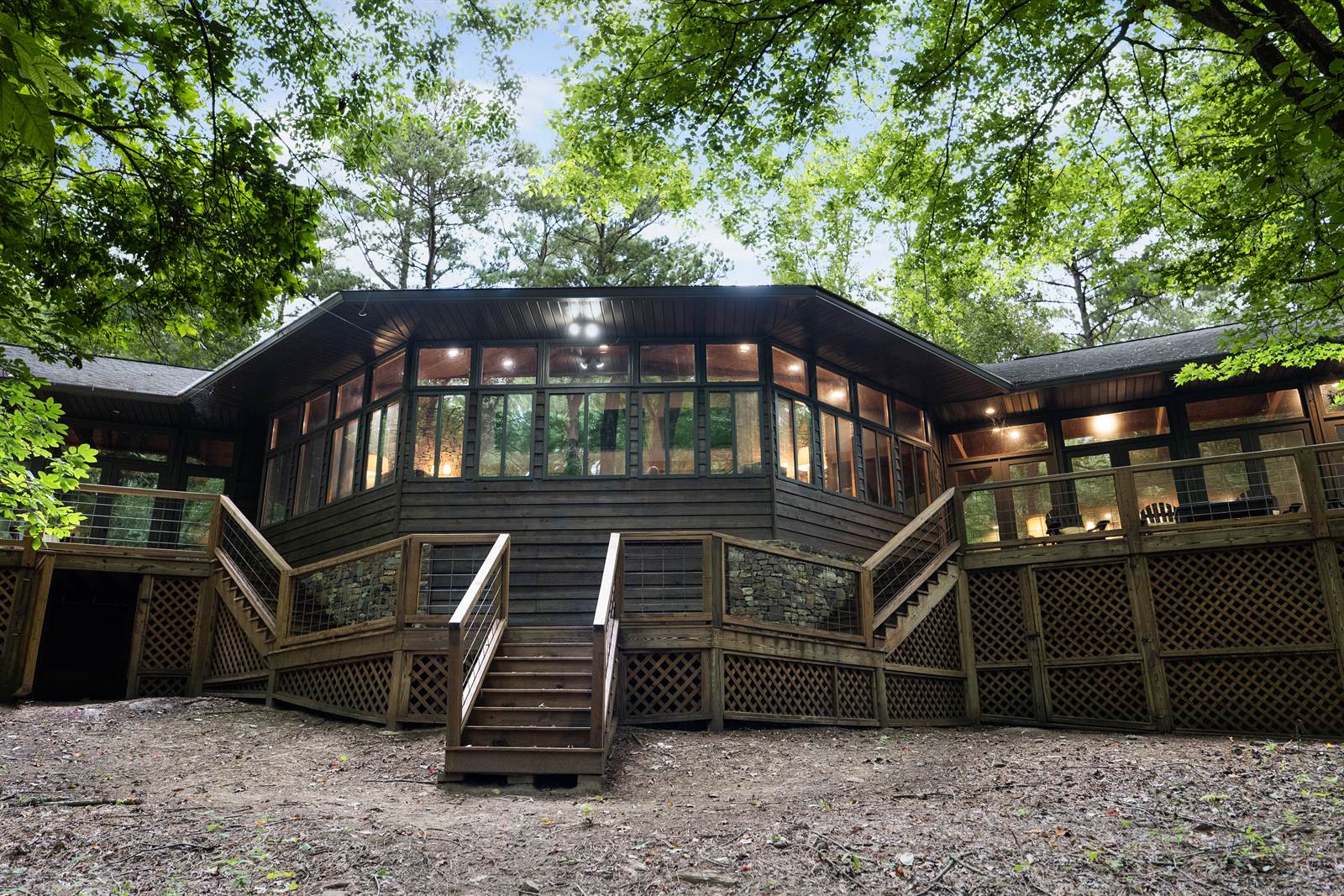 The lodge in the woods, a wall of windows above a wrap-around deck