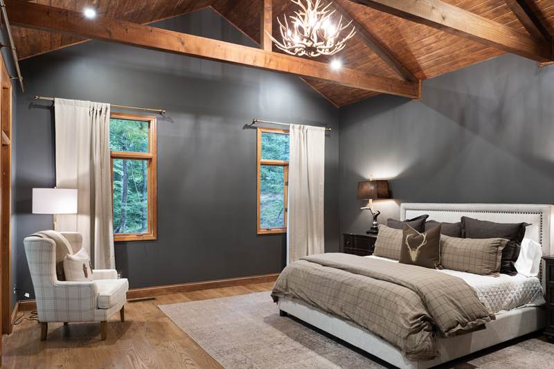 A bedroom with a king bed under exposed rafters