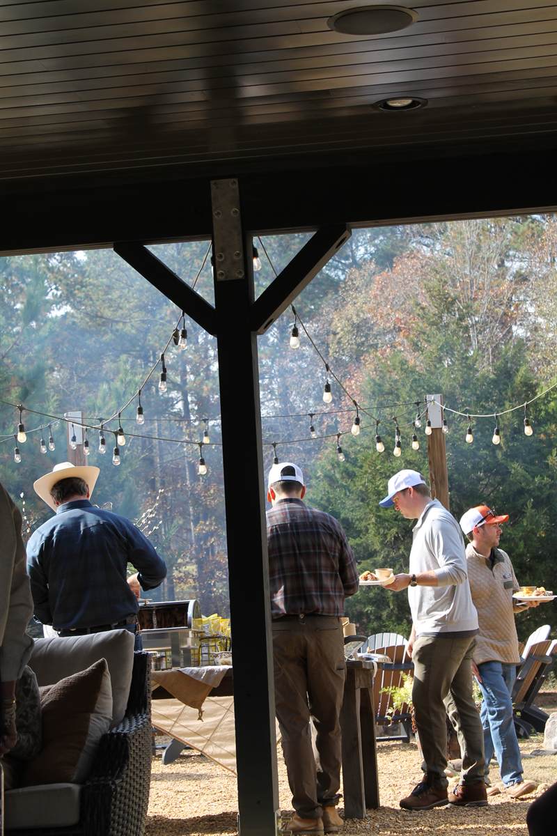Guests standing under the pavilion roof looking out over the field after a shoot